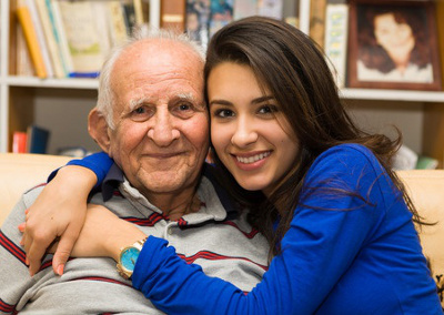 Smiling young woman sitting with an elderly man in need of care